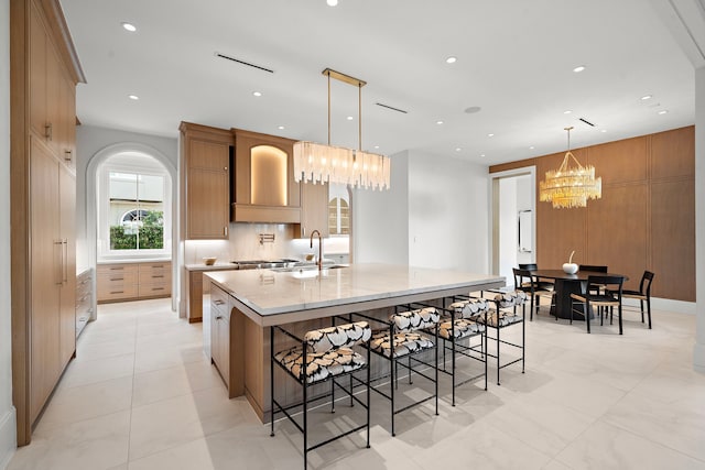 3649 Chevy Chase Dr, Houston, TX 77019 - kitchen with a chandelier, a large island, arched walkways, a breakfast bar area, and hanging light fixtures