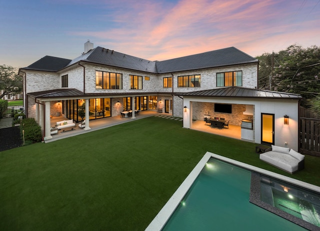 3649 Chevy Chase Dr, Houston, TX 77019 - back of house at dusk with a patio, an outdoor pool, a chimney, an outdoor hangout area, and a standing seam roof