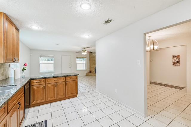 11611 Old Telegraph Rd, Houston, TX 77067 - kitchen with light tile patterned flooring, brown cabinetry, a textured ceiling, ceiling fan, and a peninsula