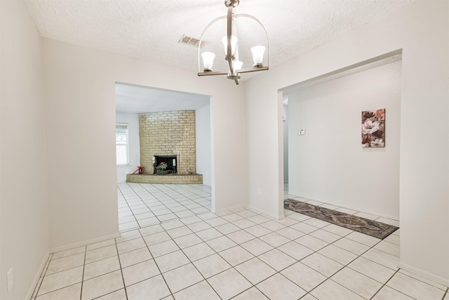 11611 Old Telegraph Rd, Houston, TX 77067 - spare room with a chandelier, a textured ceiling, light tile patterned floors, and a brick fireplace