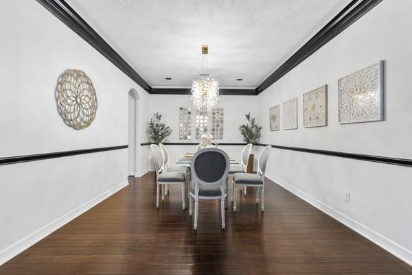 2523 Watts St, Houston, TX 77030 - dining area featuring a chandelier, ornamental molding, arched walkways, and wood finished floors