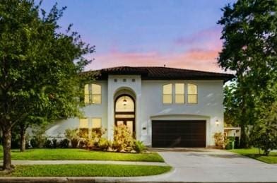 2523 Watts St, Houston, TX 77030 - mediterranean / spanish-style house with concrete driveway, an attached garage, a front lawn, and stucco siding