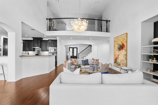 2523 Watts St, Houston, TX 77030 - living area with arched walkways, a towering ceiling, a chandelier, stairway, and dark wood-type flooring