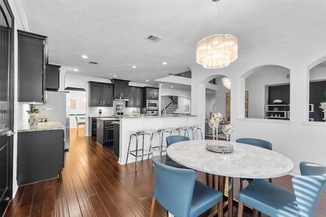 2523 Watts St, Houston, TX 77030 - dining room with dark wood-style flooring, a chandelier, arched walkways, recessed lighting, and crown molding
