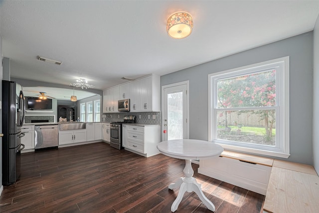 16410 Great Frst, Humble, TX 77346 - kitchen with appliances with stainless steel finishes, white cabinets, dark wood-type flooring, decorative backsplash, and a ceiling fan
