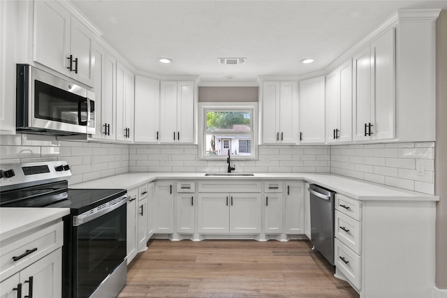 318 Primrose Rd, Jones Creek, TX 77541 - kitchen featuring appliances with stainless steel finishes, white cabinets, light wood-style flooring, recessed lighting, and light countertops