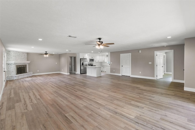 318 Primrose Rd, Jones Creek, TX 77541 - unfurnished living room featuring a ceiling fan, recessed lighting, light wood-style floors, and a brick fireplace