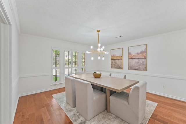 6711 Walton Heath Dr, Houston, TX 77069 - dining area with a chandelier, crown molding, light wood-style flooring, and a textured ceiling