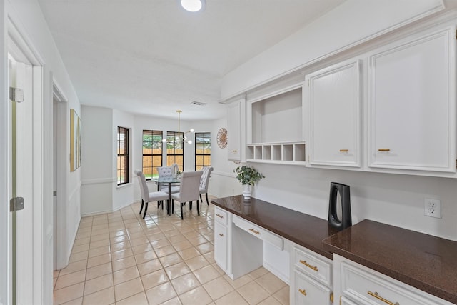 6711 Walton Heath Dr, Houston, TX 77069 - kitchen featuring dark countertops, built in study area, light tile patterned floors, open shelves, and white cabinets