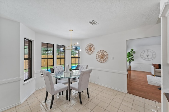 6711 Walton Heath Dr, Houston, TX 77069 - dining area featuring light tile patterned floors, a chandelier, and a textured ceiling