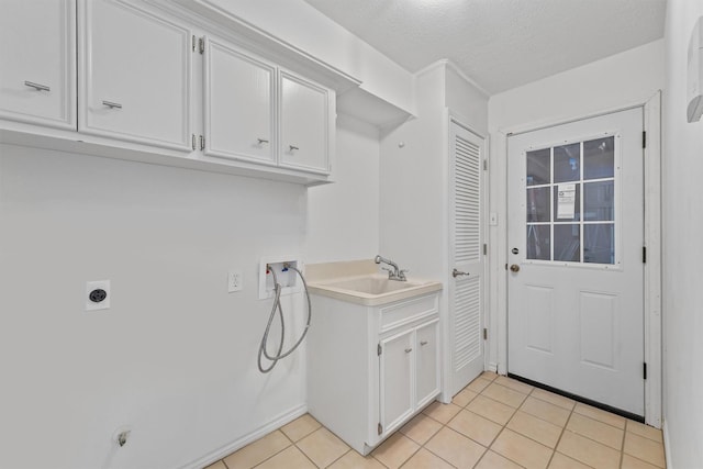 6711 Walton Heath Dr, Houston, TX 77069 - laundry room featuring hookup for a washing machine, electric dryer hookup, light tile patterned floors, cabinet space, and a textured ceiling