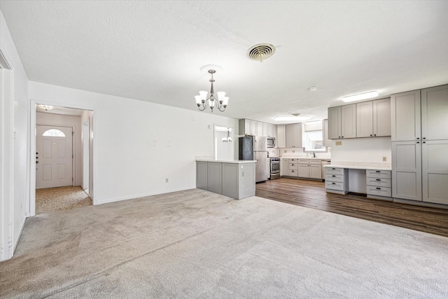 5730 Cartagena St, Houston, TX 77035 - kitchen with gray cabinetry, appliances with stainless steel finishes, dark carpet, a chandelier, and light countertops
