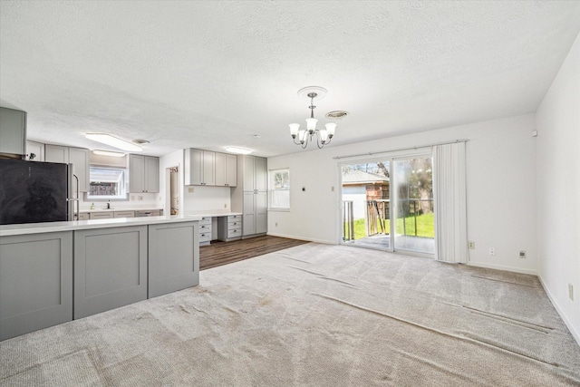 5730 Cartagena St, Houston, TX 77035 - kitchen featuring gray cabinets, freestanding refrigerator, a chandelier, a textured ceiling, and carpet