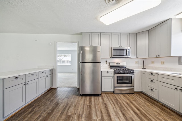 5730 Cartagena St, Houston, TX 77035 - kitchen with stainless steel appliances, gray cabinetry, a textured ceiling, dark wood-type flooring, and light countertops