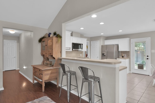 155 Fairwind Trail Dr, Conroe, TX 77385 - kitchen featuring appliances with stainless steel finishes, light countertops, a peninsula, a breakfast bar, and white cabinets