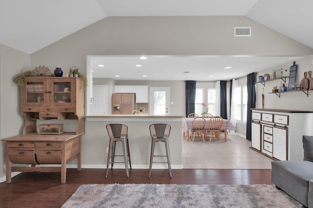 155 Fairwind Trail Dr, Conroe, TX 77385 - kitchen featuring vaulted ceiling, stainless steel fridge, a kitchen bar, a peninsula, and light wood-type flooring