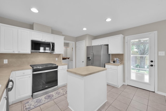 155 Fairwind Trail Dr, Conroe, TX 77385 - kitchen with stainless steel appliances, light countertops, white cabinetry, a center island, and washer / clothes dryer