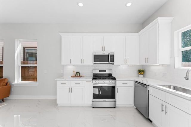 7407 Cora St, Houston, TX 77088 - kitchen with appliances with stainless steel finishes, decorative backsplash, white cabinetry, light marble finish flooring, and recessed lighting