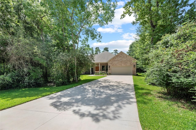 25010 Butler Hill Ct, Tomball, TX 77375 - view of property hidden behind natural elements with concrete driveway, a garage, a front yard, and brick siding