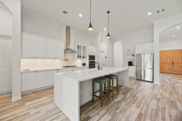 25010 Butler Hill Ct, Tomball, TX 77375 - kitchen featuring stainless steel appliances, wall chimney exhaust hood, arched walkways, ornamental molding, and backsplash