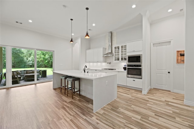 25010 Butler Hill Ct, Tomball, TX 77375 - kitchen with appliances with stainless steel finishes, wall chimney range hood, light countertops, white cabinetry, and light wood-type flooring
