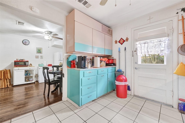 1012 Joyce St, Houston, TX 77009 - kitchen featuring a ceiling fan, light tile patterned flooring, light countertops, blue cabinets, and ornamental molding