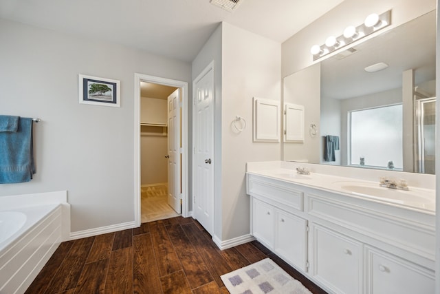 3282 Bend Cove Ct, League City, TX 77573 - bathroom featuring wood finished floors, double vanity, a shower stall, a garden tub, and a walk in closet