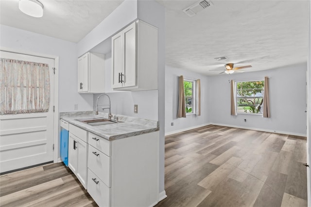 514 E Foley St, Alvin, TX 77511 - kitchen featuring ceiling fan, light countertops, white cabinets, light wood-style floors, and a textured ceiling