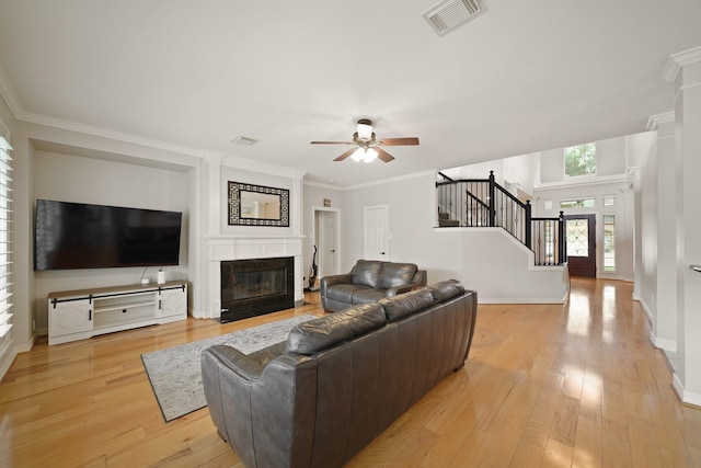 14210 Northface Manor Ct, Cypress, TX 77429 - living area featuring a ceiling fan, stairs, a fireplace with flush hearth, light wood finished floors, and ornamental molding