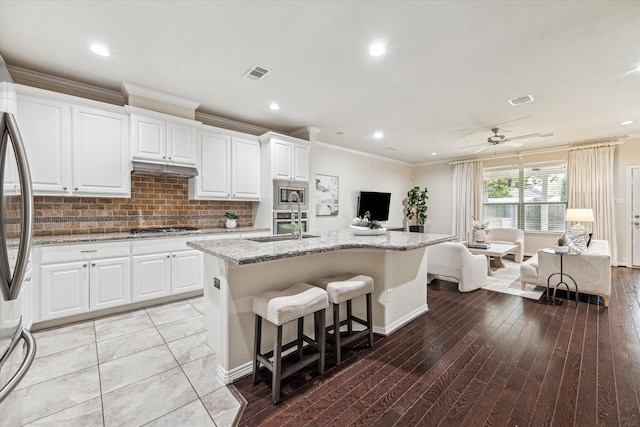831 W 26th St, Houston, TX 77008 - kitchen featuring appliances with stainless steel finishes, open floor plan, light stone countertops, a kitchen island with sink, and backsplash