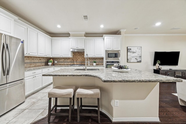 831 W 26th St, Houston, TX 77008 - kitchen featuring stainless steel appliances, ornamental molding, under cabinet range hood, backsplash, and white cabinetry