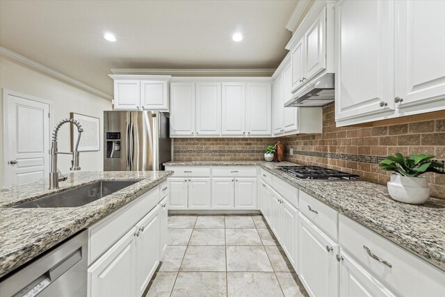 831 W 26th St, Houston, TX 77008 - kitchen with stainless steel appliances, under cabinet range hood, ornamental molding, decorative backsplash, and white cabinets