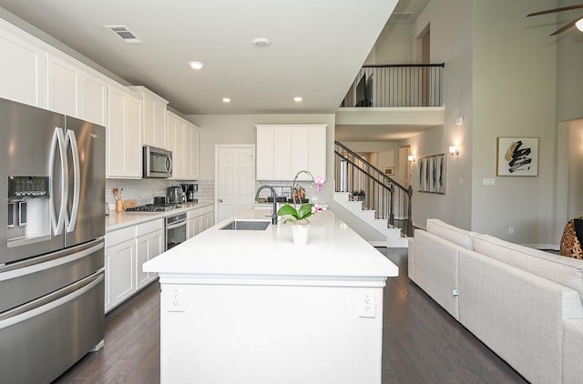 24311 Orley Island Ct, Katy, TX 77493 - kitchen with appliances with stainless steel finishes, dark wood-style flooring, open floor plan, tasteful backsplash, and an island with sink