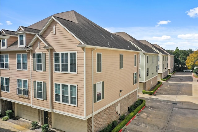 3001 Murworth Dr Unit 1606, Houston, TX 77025 - view of side of home featuring brick siding, concrete driveway, a garage, and roof with shingles