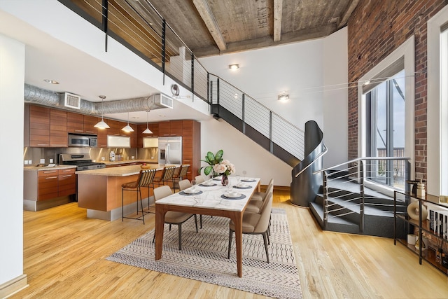 915 Franklin St Unit 9L, Houston, TX 77002 - dining area with a high ceiling, light wood-style flooring, and brick wall