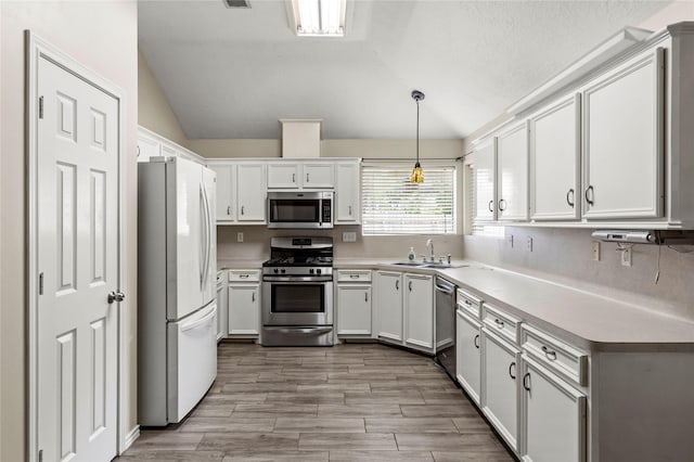 110 Rustling Wind Dr, Montgomery, TX 77356 - kitchen with appliances with stainless steel finishes, vaulted ceiling, white cabinetry, light countertops, and pendant lighting
