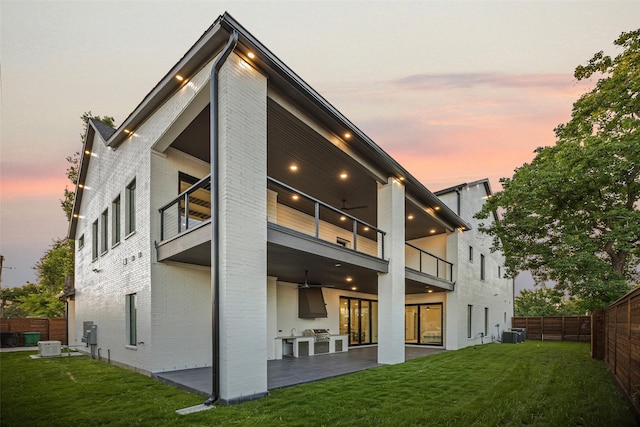 431 W 30th St, Houston, TX 77018 - back of house at dusk featuring a balcony, brick siding, a fenced backyard, and a patio