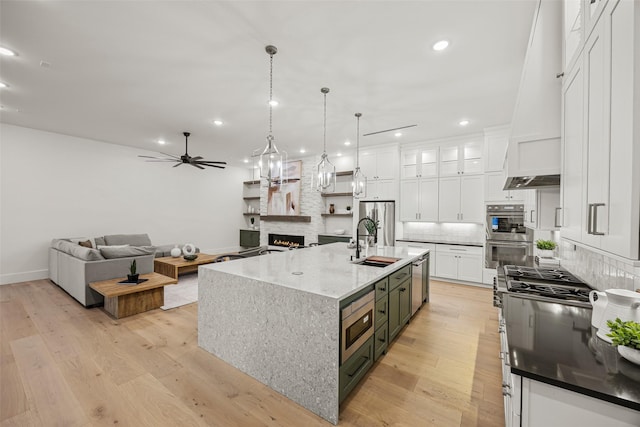 431 W 30th St, Houston, TX 77018 - kitchen with appliances with stainless steel finishes, custom range hood, white cabinetry, backsplash, and a fireplace