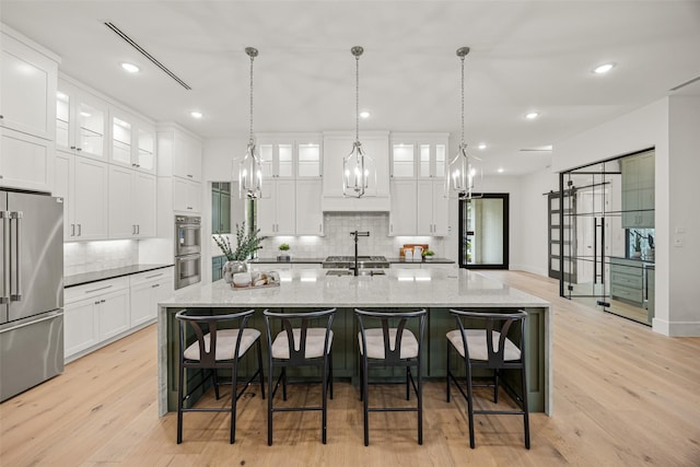 431 W 30th St, Houston, TX 77018 - kitchen with stainless steel appliances, backsplash, a chandelier, white cabinetry, and a large island