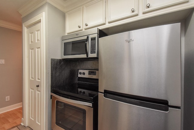 9005 Gaylord St Unit 19, Houston, TX 77024 - kitchen with appliances with stainless steel finishes, ornamental molding, white cabinetry, and light wood finished floors