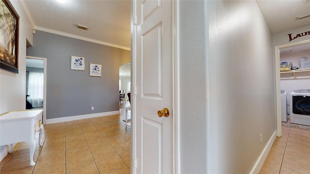 1309 Bayswater Dr, Houston, TX 77047 - hall featuring arched walkways, light tile patterned floors, ornamental molding, and washer and clothes dryer
