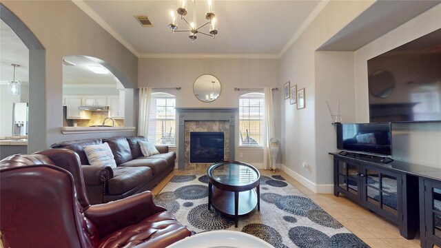 1309 Bayswater Dr, Houston, TX 77047 - living room with a tile fireplace, arched walkways, a chandelier, light tile patterned floors, and crown molding