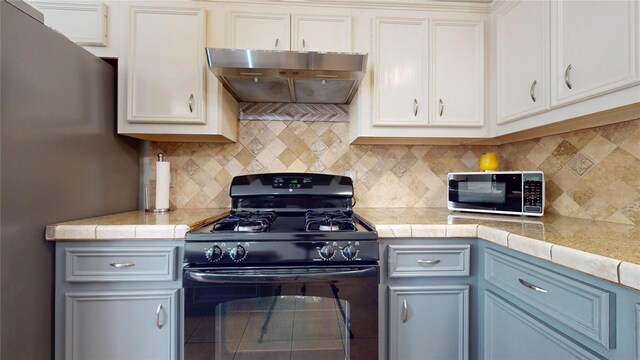 1309 Bayswater Dr, Houston, TX 77047 - kitchen with gas stove, custom exhaust hood, decorative backsplash, and freestanding refrigerator