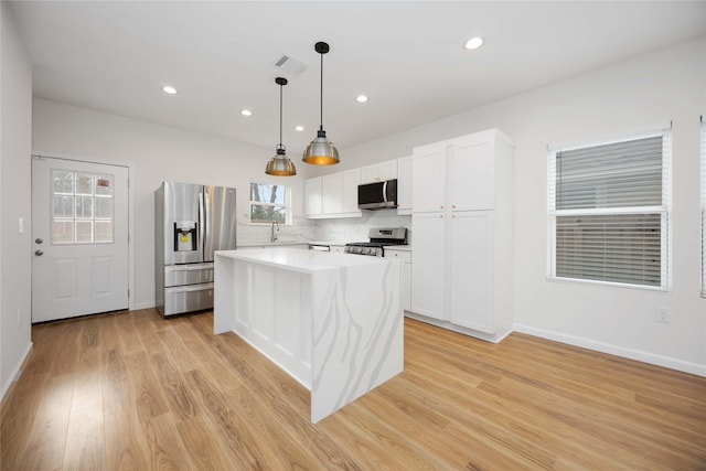 8923 De Priest St, Houston, TX 77088 - kitchen featuring appliances with stainless steel finishes, light wood-style floors, white cabinets, tasteful backsplash, and light countertops