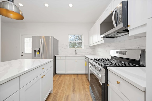 8923 De Priest St, Houston, TX 77088 - kitchen featuring appliances with stainless steel finishes, backsplash, white cabinetry, recessed lighting, and light wood finished floors