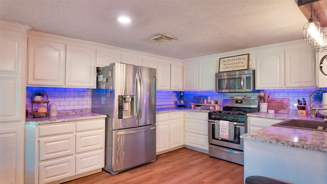 141 Cypress Dr, Richwood, TX 77531 - kitchen with stainless steel appliances, tasteful backsplash, light wood finished floors, white cabinetry, and ornamental molding