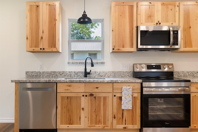 228 Cherry, Lexington, TX 78947 - kitchen with stainless steel appliances, light brown cabinetry, light stone countertops, and pendant lighting