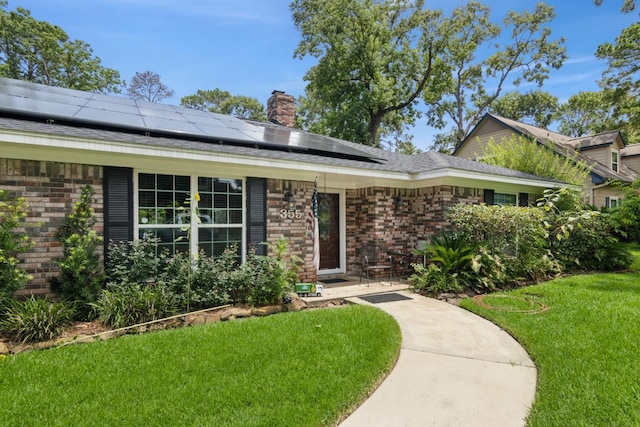 355 Cumberland Trl, Conroe, TX 77302 - view of front of home with brick siding, a front lawn, roof mounted solar panels, and a chimney