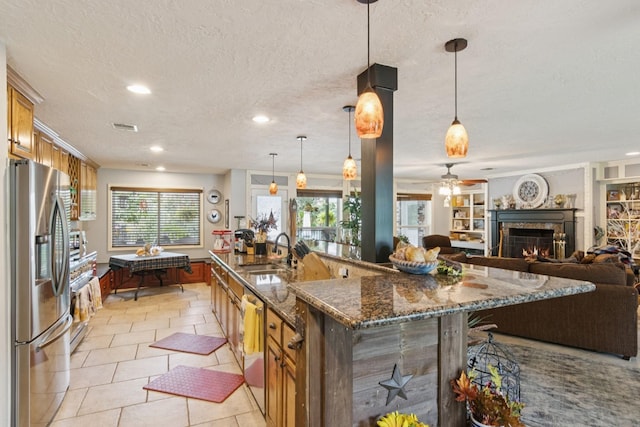 355 Cumberland Trl, Conroe, TX 77302 - kitchen with stainless steel appliances, a warm lit fireplace, a textured ceiling, open floor plan, and a ceiling fan