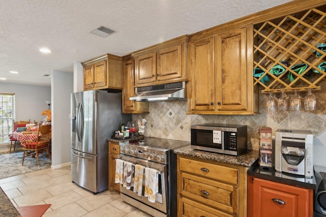 355 Cumberland Trl, Conroe, TX 77302 - kitchen with appliances with stainless steel finishes, under cabinet range hood, backsplash, brown cabinets, and recessed lighting